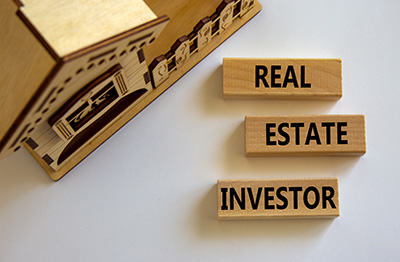 Real estate investor symbol. Wooden blocks with words 'Real estate investor' near miniature house. Beautiful white background. Business and real estate investor concept, copy space.