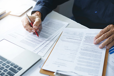 businessman reviewing document reports at office workplace with computer laptop. legal expert, professional lawyer reading and checking financial documents or insurance contract